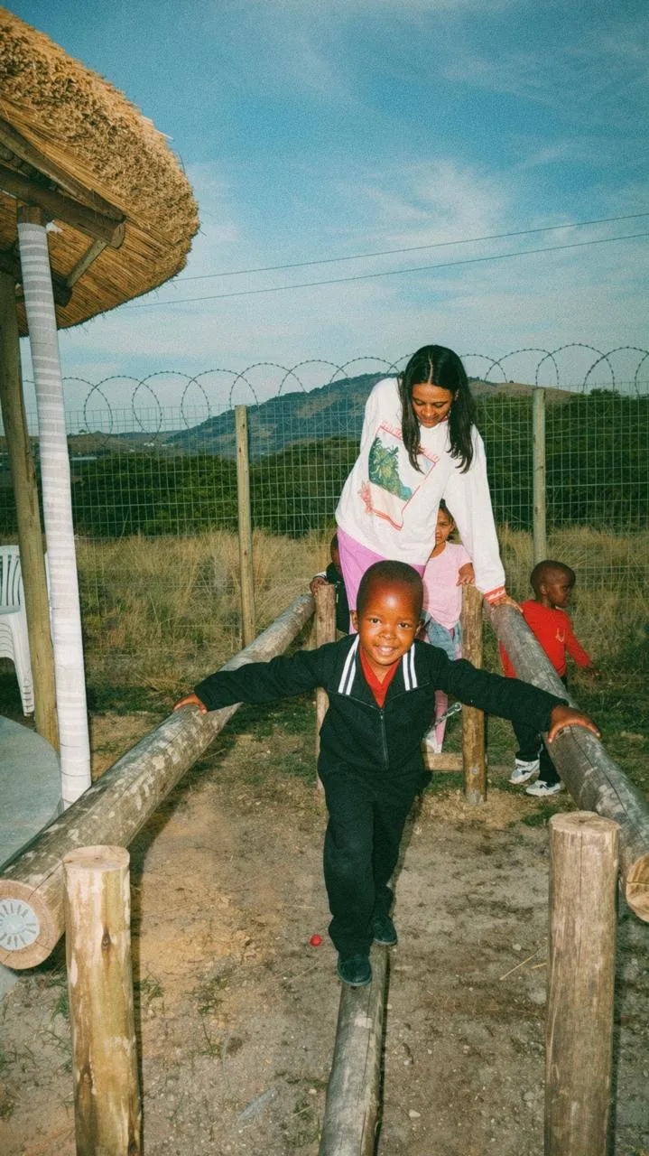 A volunteer helping children balance along a log
