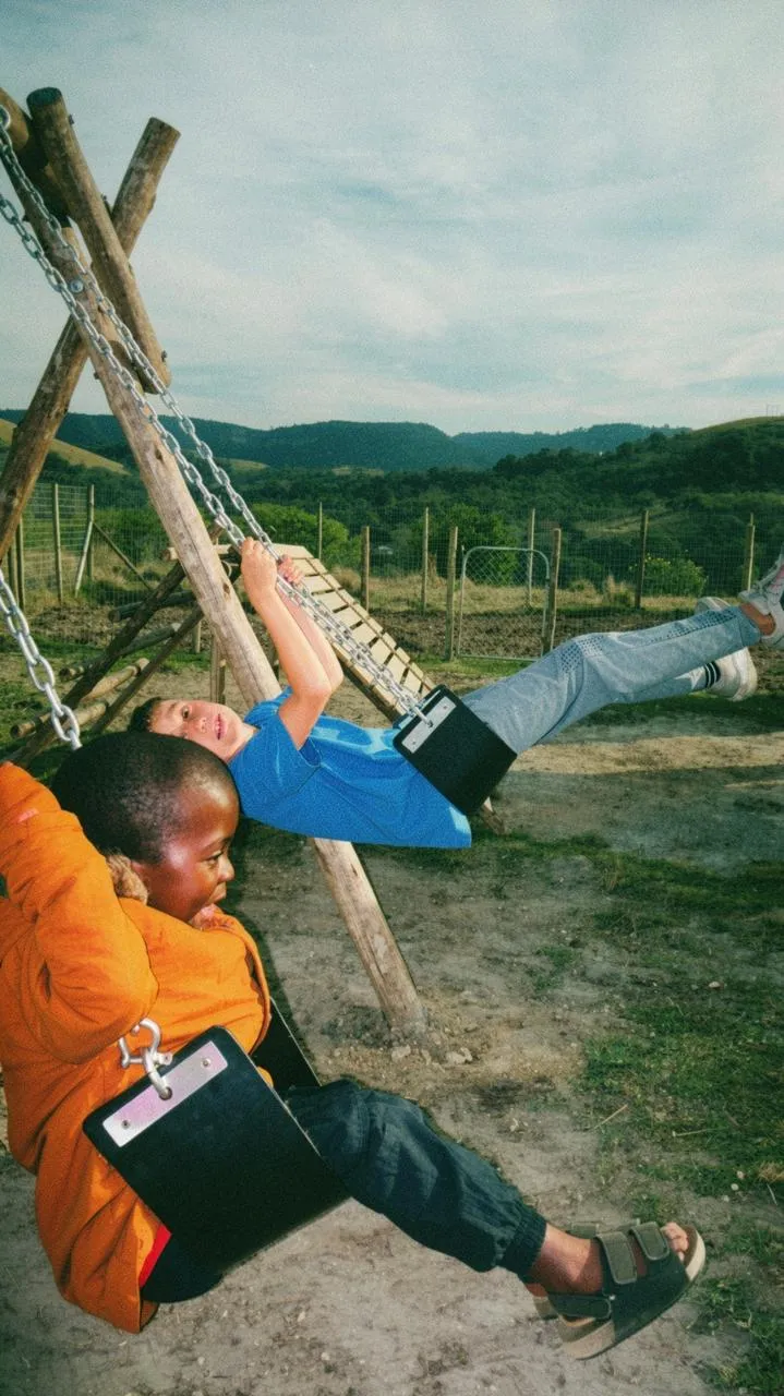 A child laughing on a swing at the Mbotyi ECD